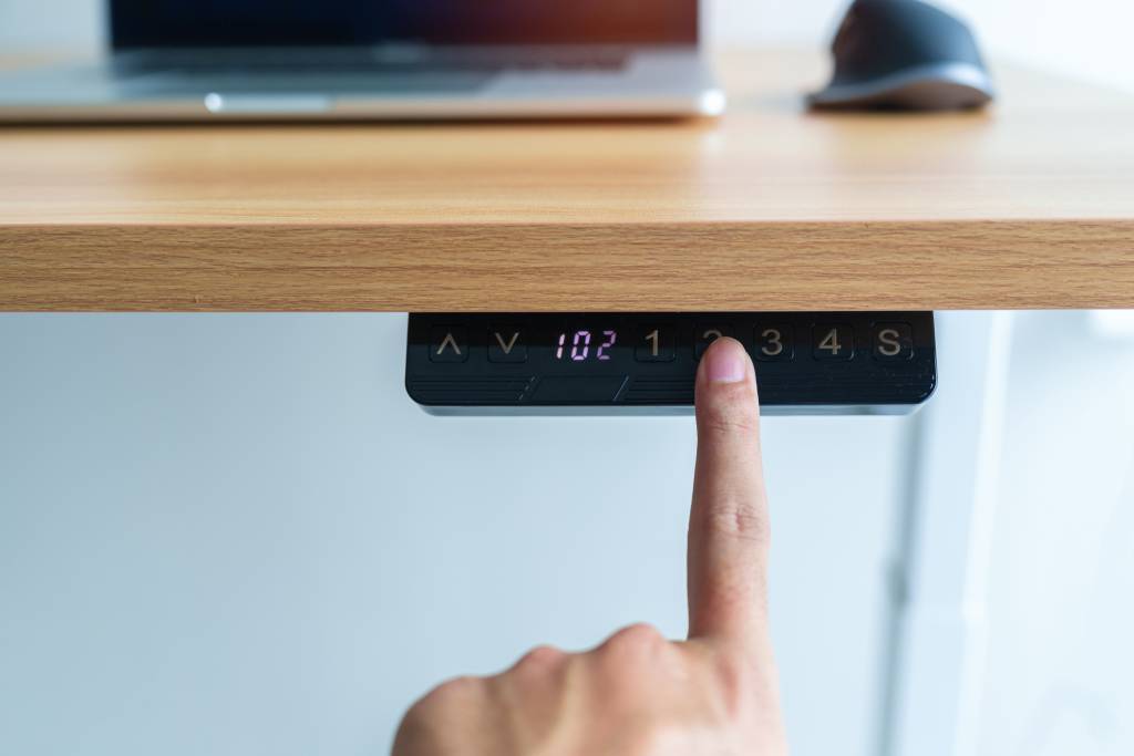 Finger pressing the button to adjust the height on a standing desk