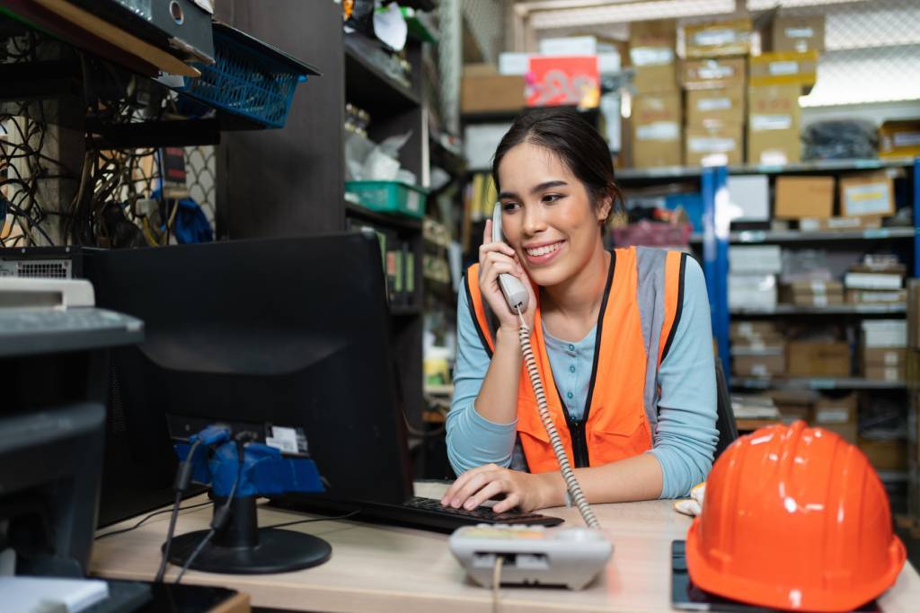 Person standing at a desk in a warehouse talking on the phone