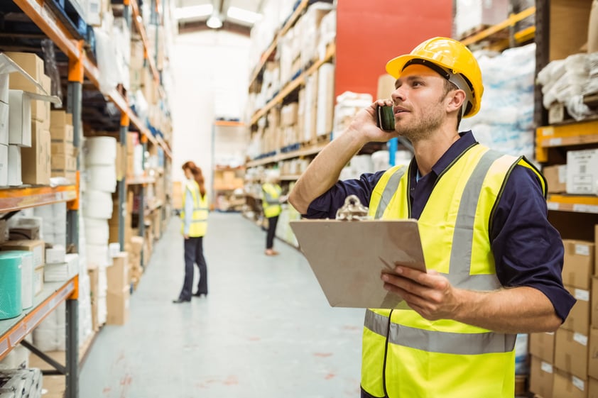 Warehouse-worker-on-phone-holding-clipboard