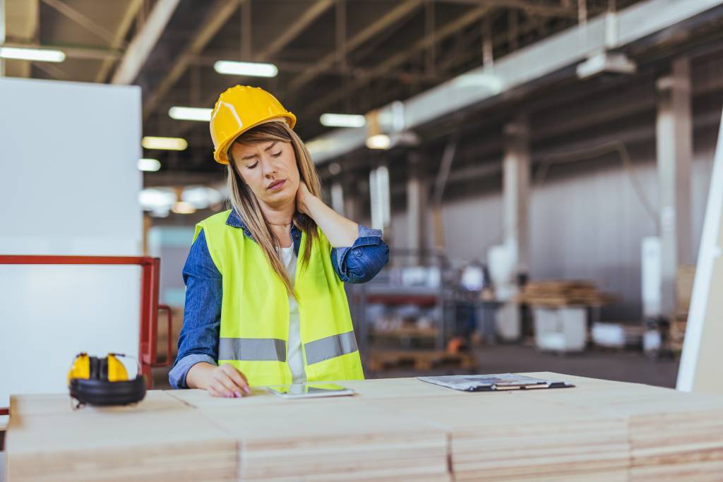 Woman wearing safety gear holding her neck because she doesn’t have the proper workstation