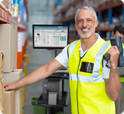 Man smiling at the camera, standing next to mobile computer cart