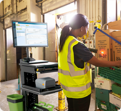 Woman working next to a Mobile Computer Workstation in warehouse setting