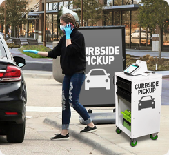 Retail worker assisting with curbside pickup using a mobile computer retail cart