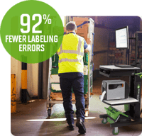 A warehouse employee pushes a cart loaded with boxes next to a mobile workstation.